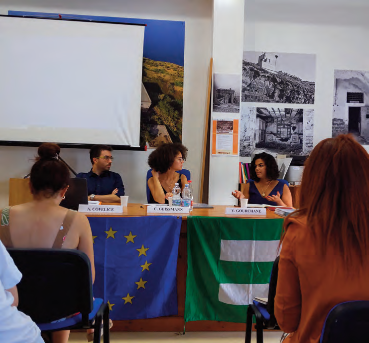 Panelists speak at the Ventotene International Seminar beneath EU and Ventotene flags