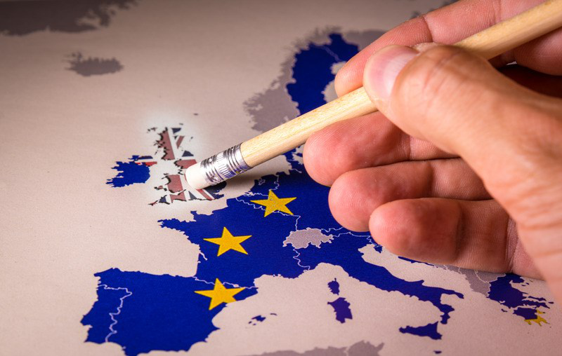 A hand paints over a map of Europe styled as the European Union flag