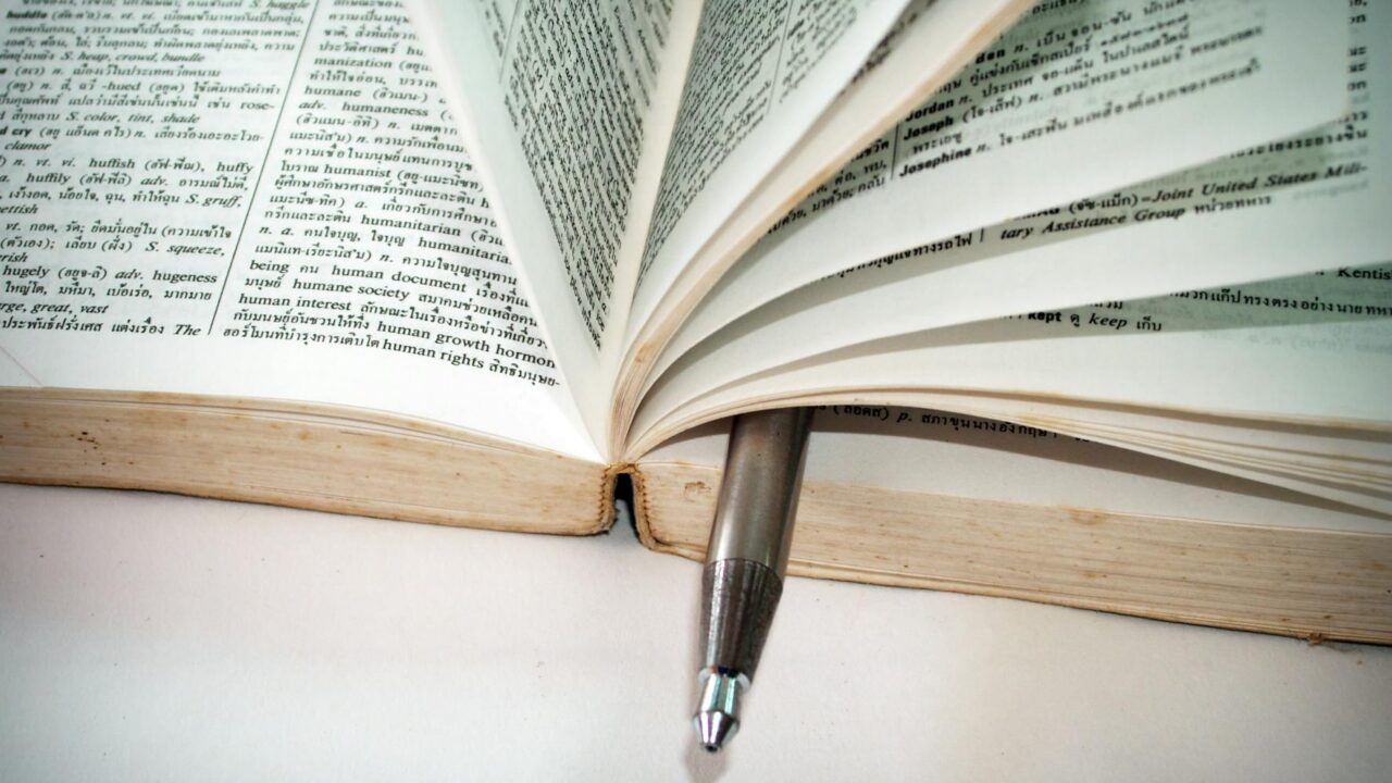 An open book with a pen on top of it, suggesting someone is reading or studying.