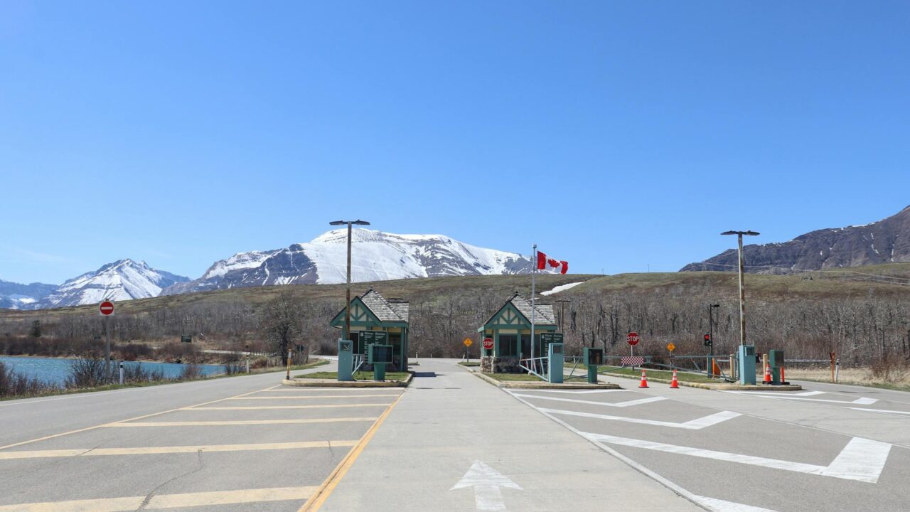 A clear day at a mountain resort with a parking lot and flags flying.