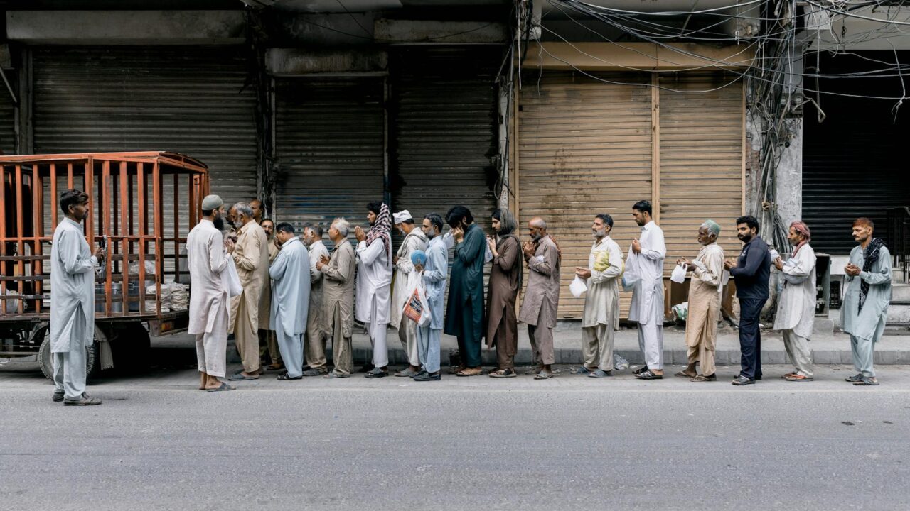 A group of men gathered on a street corner, engaged in prayer.