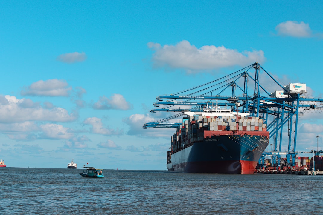 A large cargo ship docked at a port with clear skies overhead.