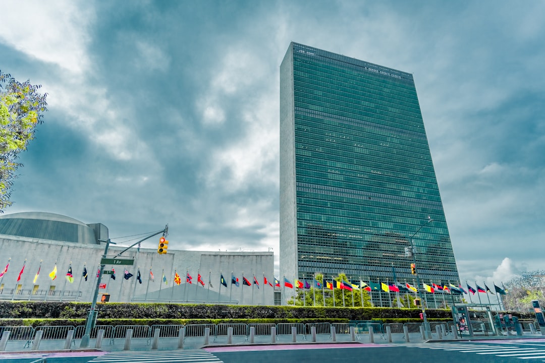 The United Nations Headquarters in New York City with flags of member states flying on the front lawn.