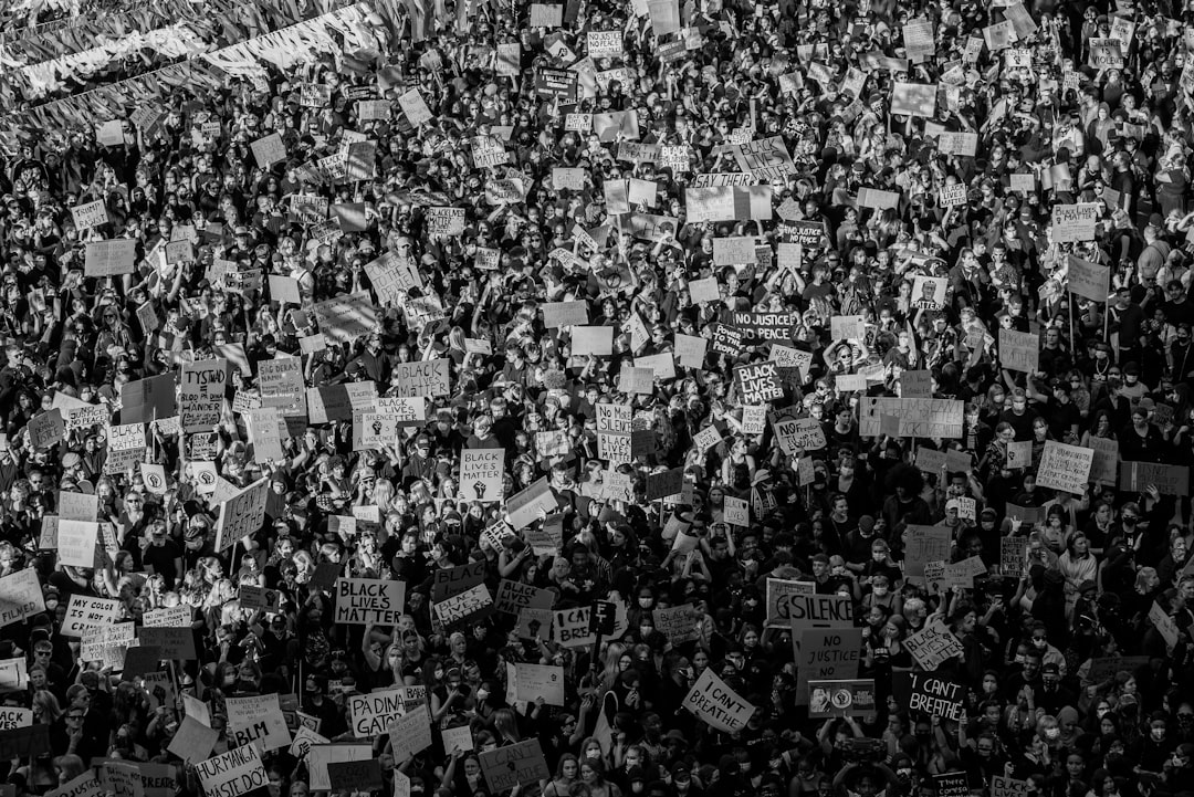 A large crowd of people holding signs and banners at a public demonstration, expressing their views on social or politic