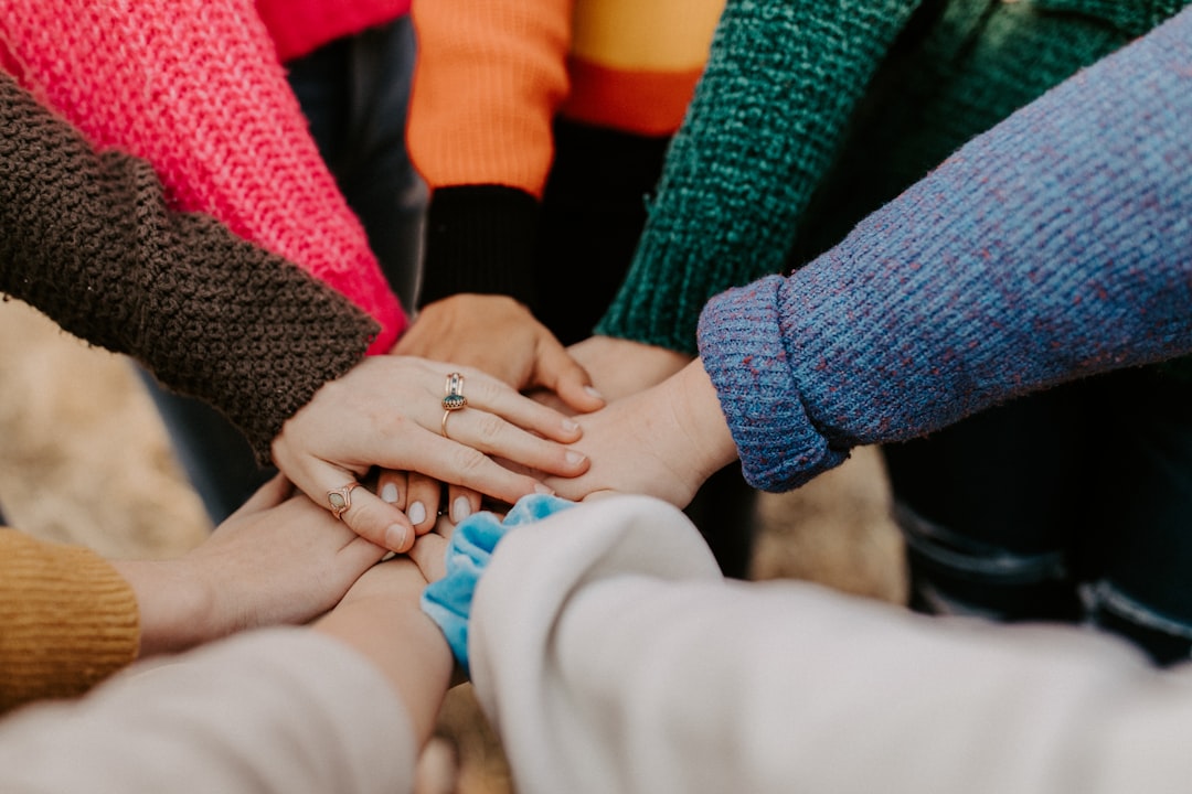 A group of people holding hands in a circle, symbolizing unity and friendship.