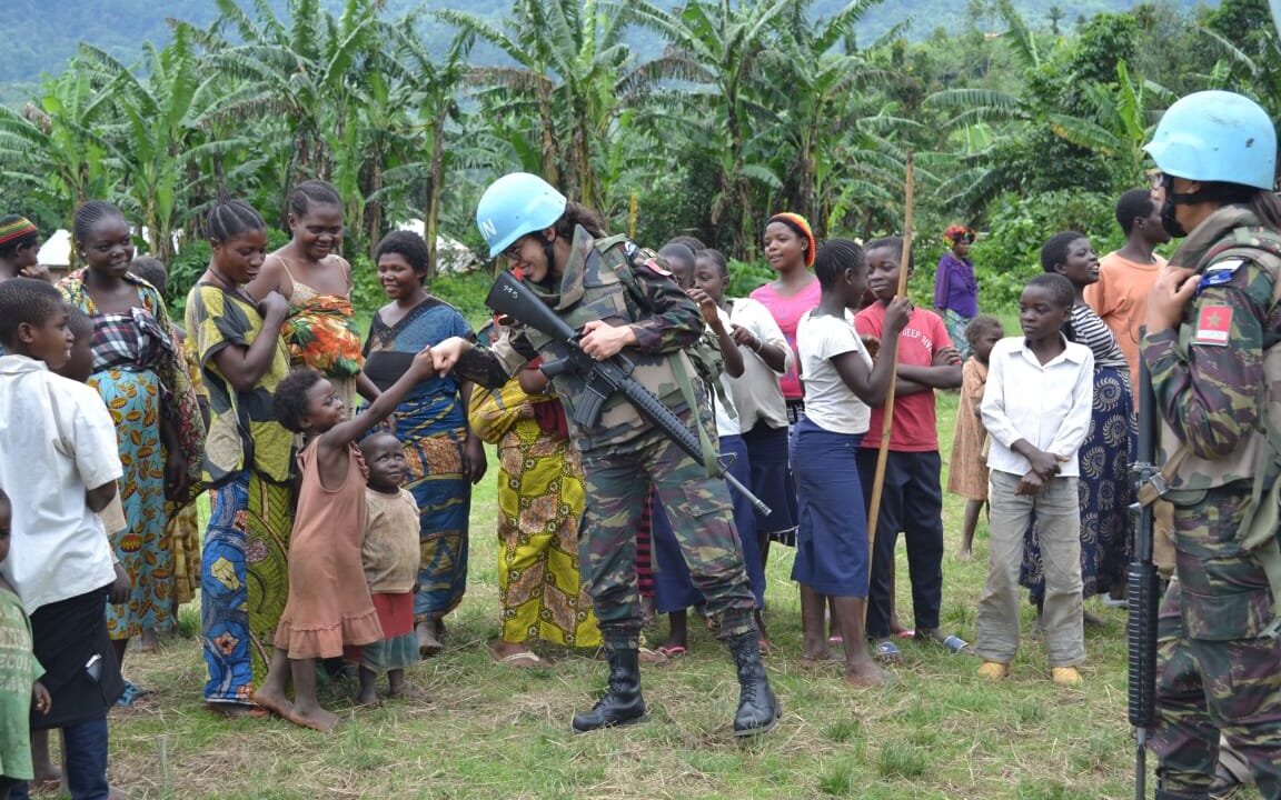 UN peacekeepers (blue helmets) gathered with local women at a community function honoring women leaders, a concrete picture of the Women, Peace and Security agenda where women's participation and protection meet a peacekeeping mission.