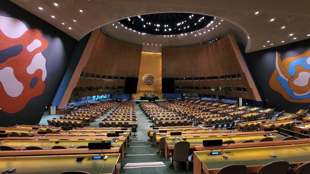The United Nations General Assembly Hall, with its gold emblem and rows of delegate desks