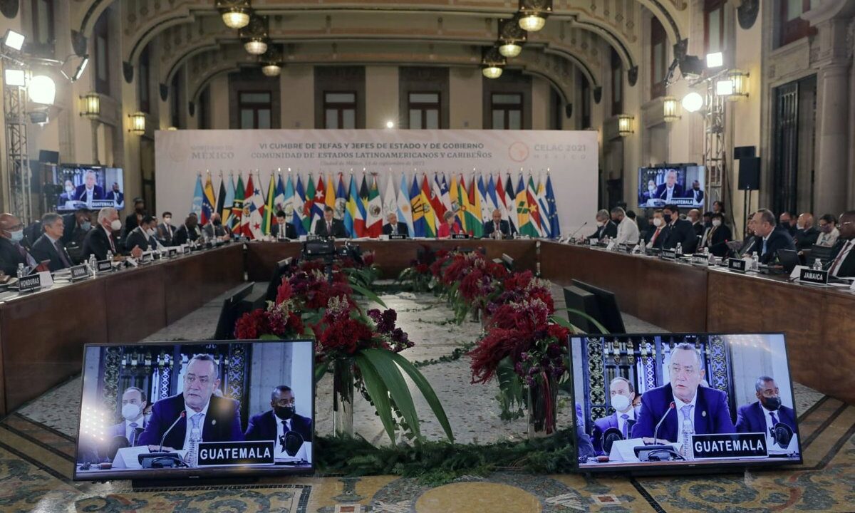 The plenary of a Community of Latin American and Caribbean States (CELAC) summit: the horseshoe table ringed with member-state flags and country nameplates, representing Latin American and Caribbean states acting collectively.