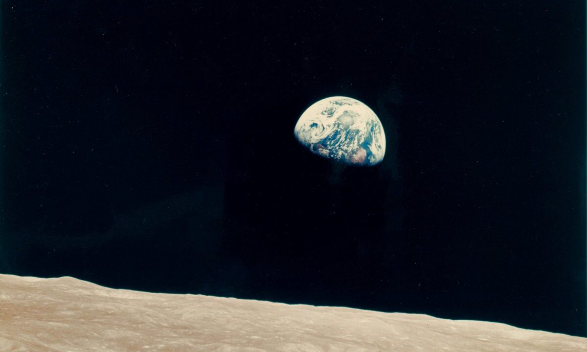 The Apollo 8 Earthrise: Earth rising as a small blue marble over the barren lunar horizon, the 1968 photograph that first let humanity see itself as one fragile world. A natural fit for a speculative letter looking back on a planet that learned to govern itself as one.