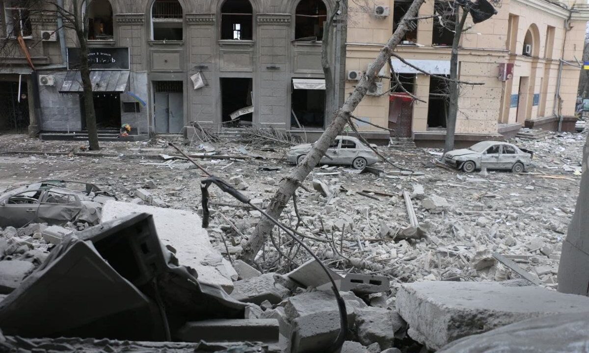 A bombarded city street in Ukraine, rubble and shattered facades, illustrating the article's point that the Ukraine conflict shows barbaric warfare is a product of the flawed war system.