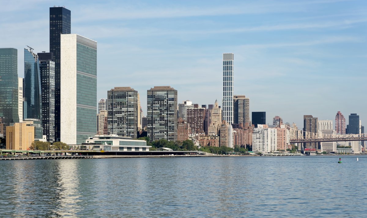 The headquarters of the United Nations in New York, the Secretariat tower and General Assembly building seen across the East River, the institutional home of the reform debate the article describes.