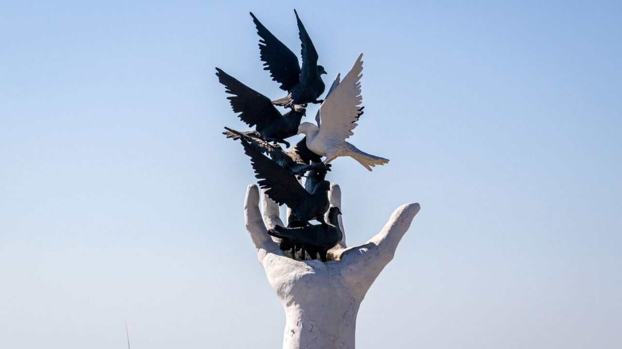 A sculpture of a hand holding a bird, symbolizing freedom or the connection between humans and nature.