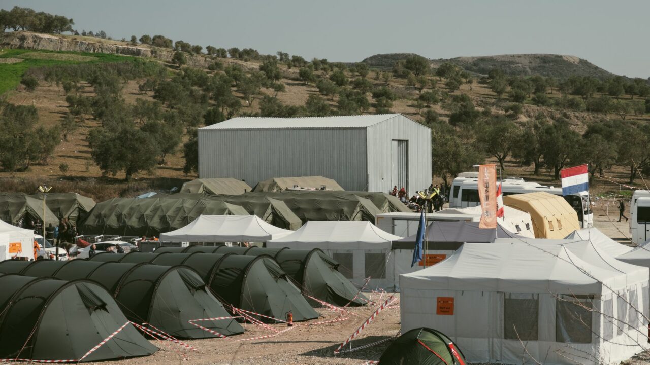 A camp set up for humanitarian aid and disaster relief, with tents and temporary structures providing shelter.