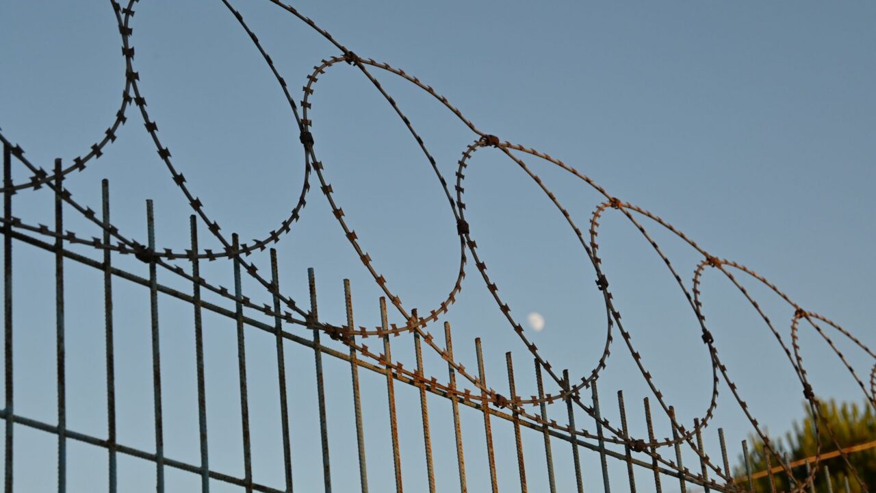 Barbed wire fence with metal poles and posts, suggesting a secure or restricted area.