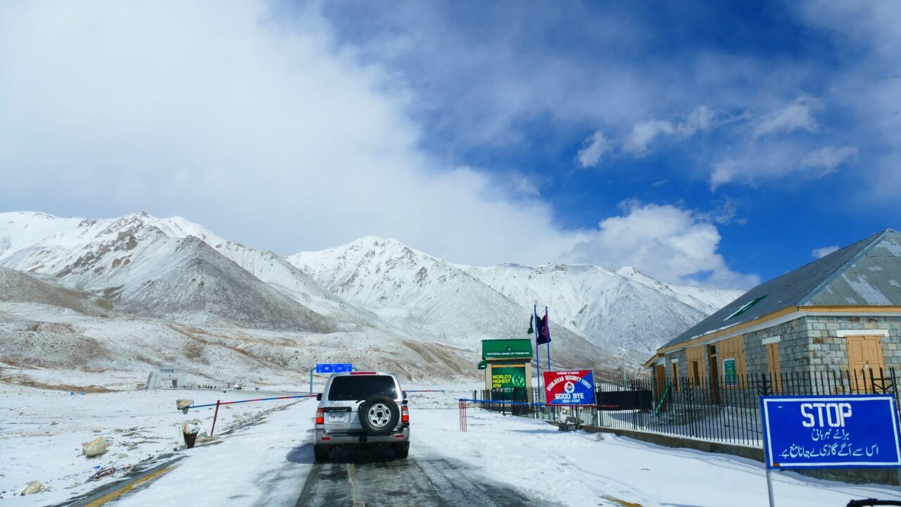 A snowy mountain road with a truck driving through a mountainous landscape.