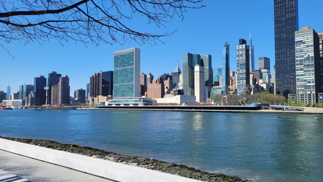 The United Nations Headquarters in New York City, with flags flying in the background.