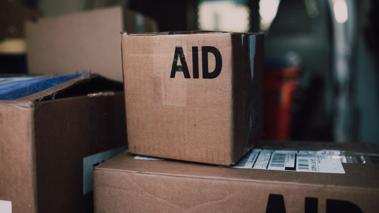 A stack of boxes with the word 'AID' written on them, indicating they contain humanitarian aid supplies.