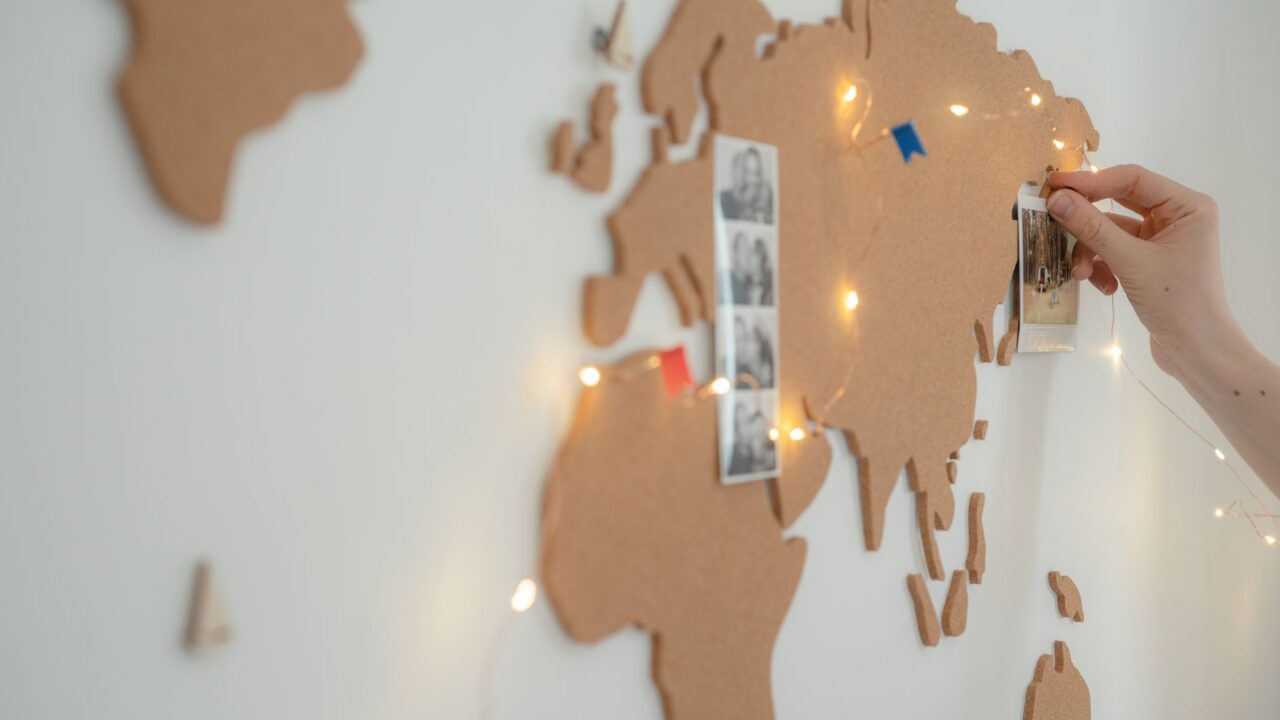Hands placing photos on a world map, creating a string of lights to connect the images.