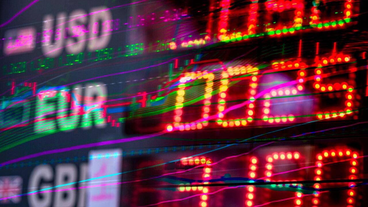 A close-up of a digital stock market display showing various currency values.