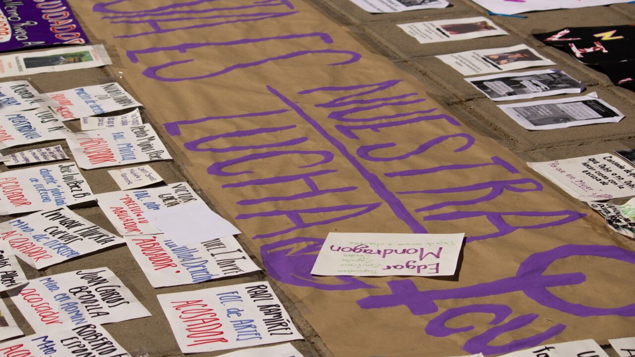 A collection of protest signs and banners on the ground, with messages of activism and social justice.