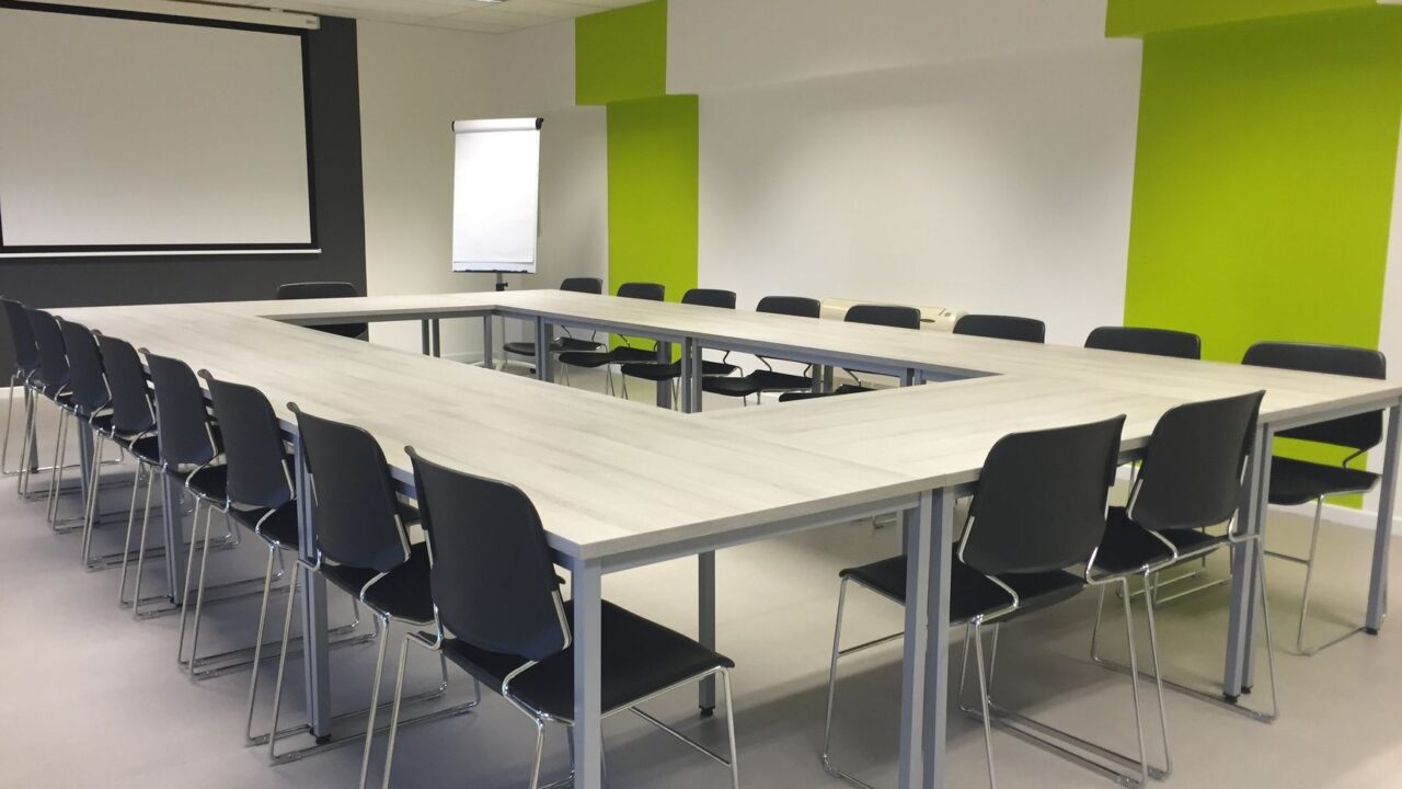 A modern conference room with a round table and chairs, ready for a meeting or presentation.
