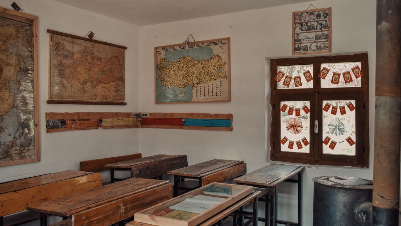 A classroom with wooden desks and a world map on the wall.