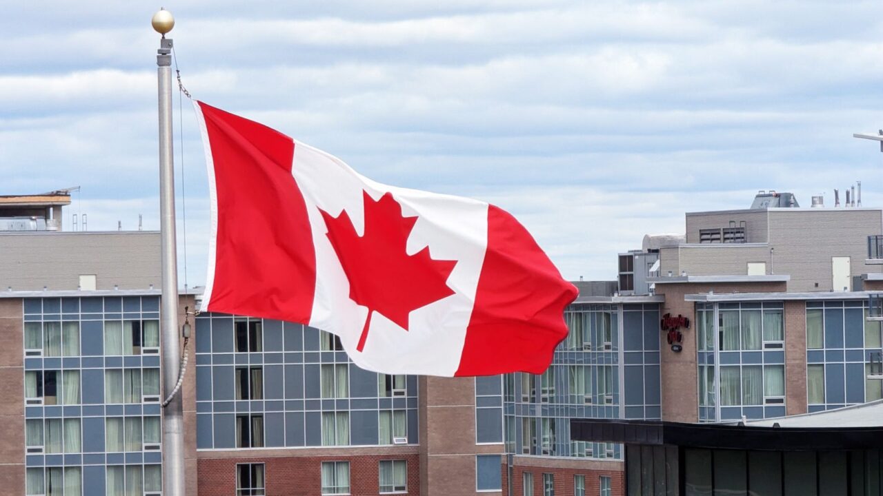 The Canadian flag flying in front of city office buildings.
