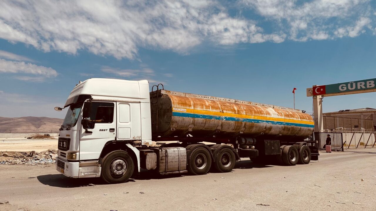 A large tanker truck parked at a fuel station in a desert environment.
