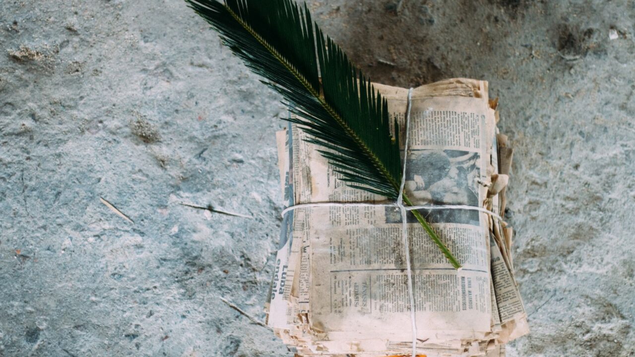 A newspaper wrapped in a twig, symbolizing the burial of news or the weight of information.