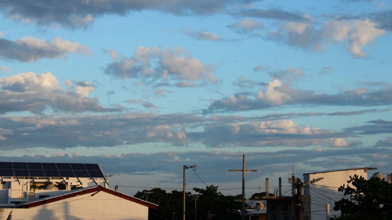 A view of a residential area with houses and clouds in the sky.