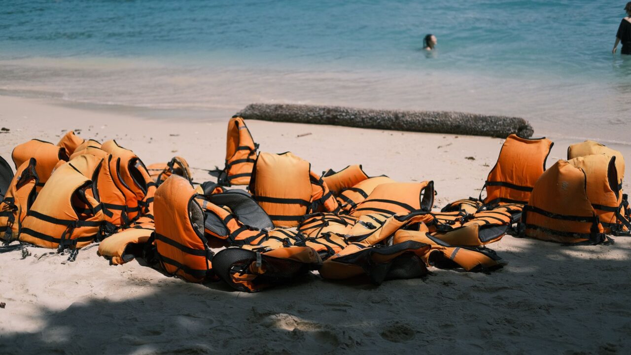 A collection of life preservers on a sandy beach, ready for use.