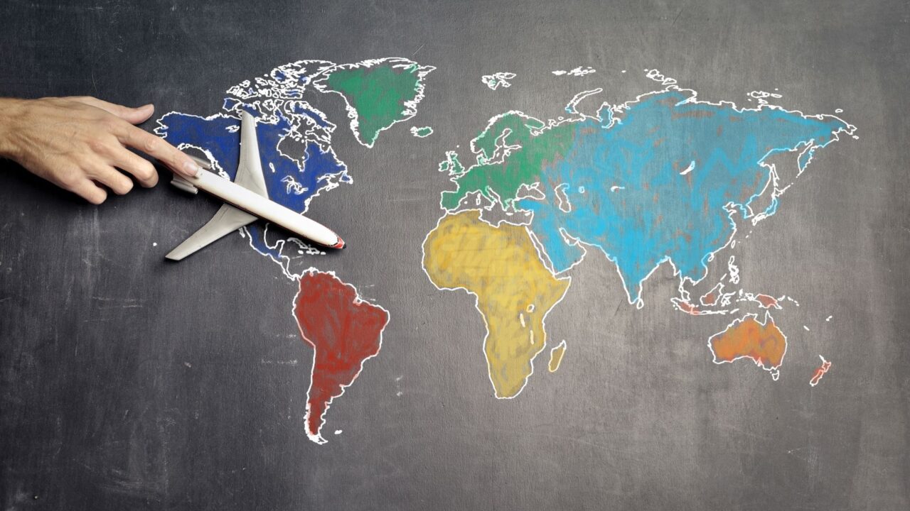 Hand touching a globe with a jet airplane on it, symbolizing global travel and connectivity.