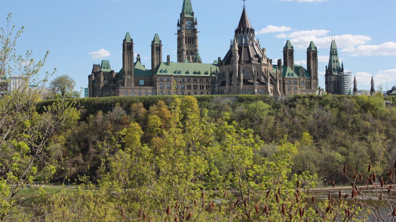 Parliament Hill in Ottawa above the trees on a sunny day.