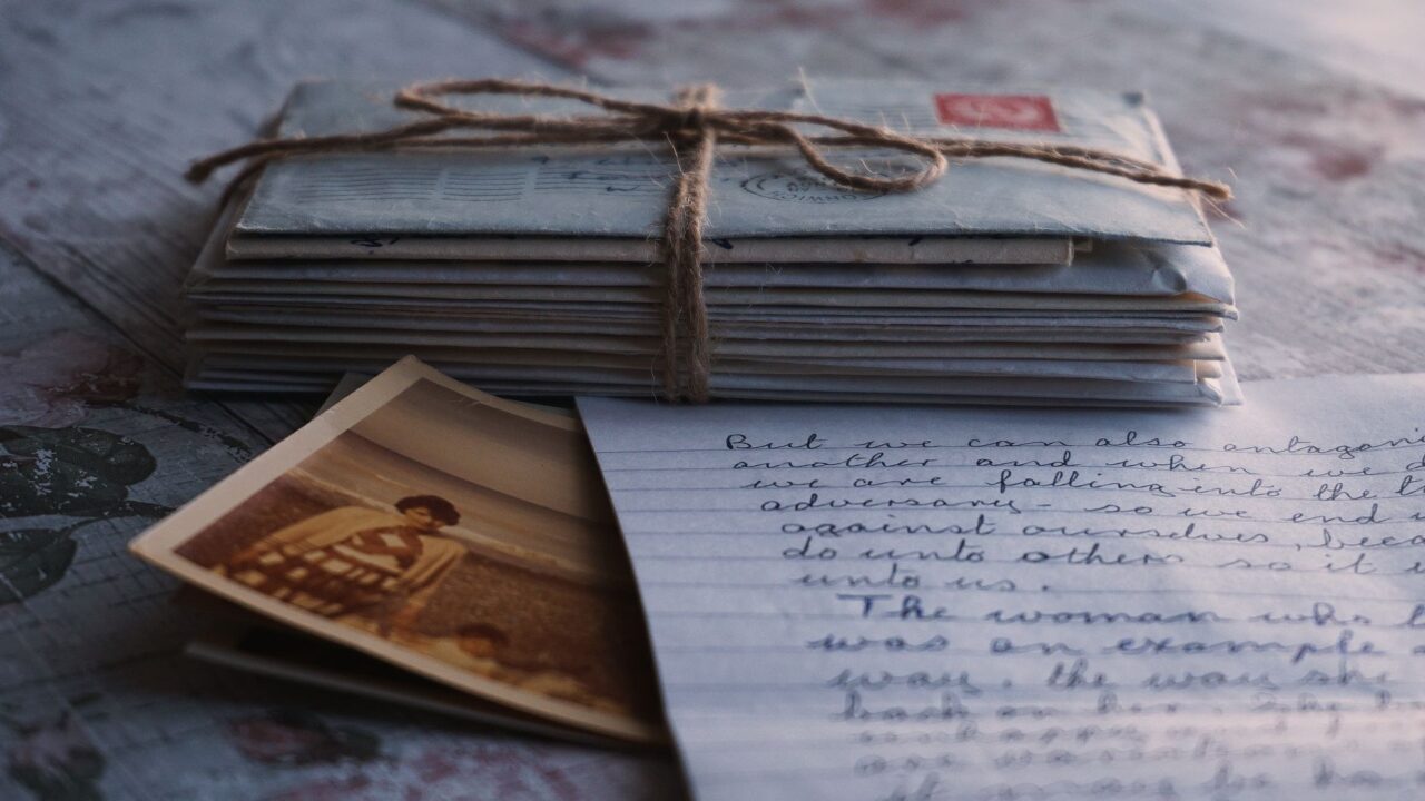 An old photograph and letters tied together with a string, evoking a sense of nostalgia and connection to the past.