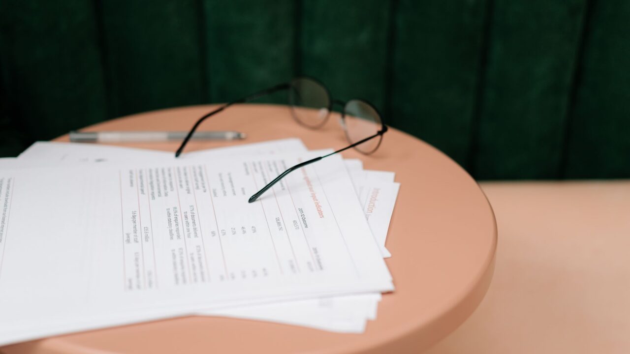 Printed report pages and spectacles on a round table.