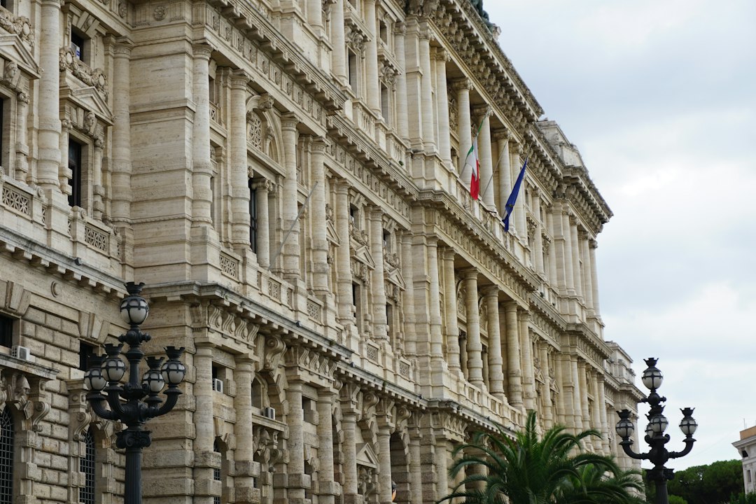 The facade of a historic building in Rome, Italy, showcasing its ornate architecture and the Italian flag flying above.