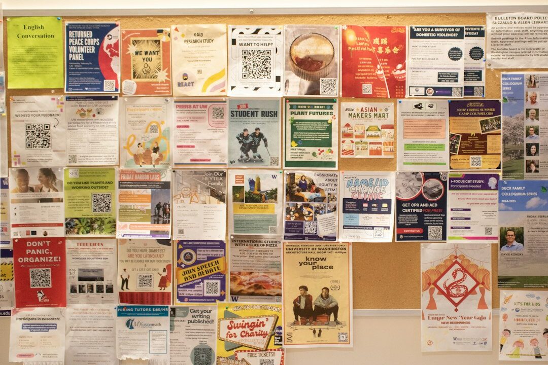 A bulletin board covered with various posters and flyers, likely containing information about events, announcements, or