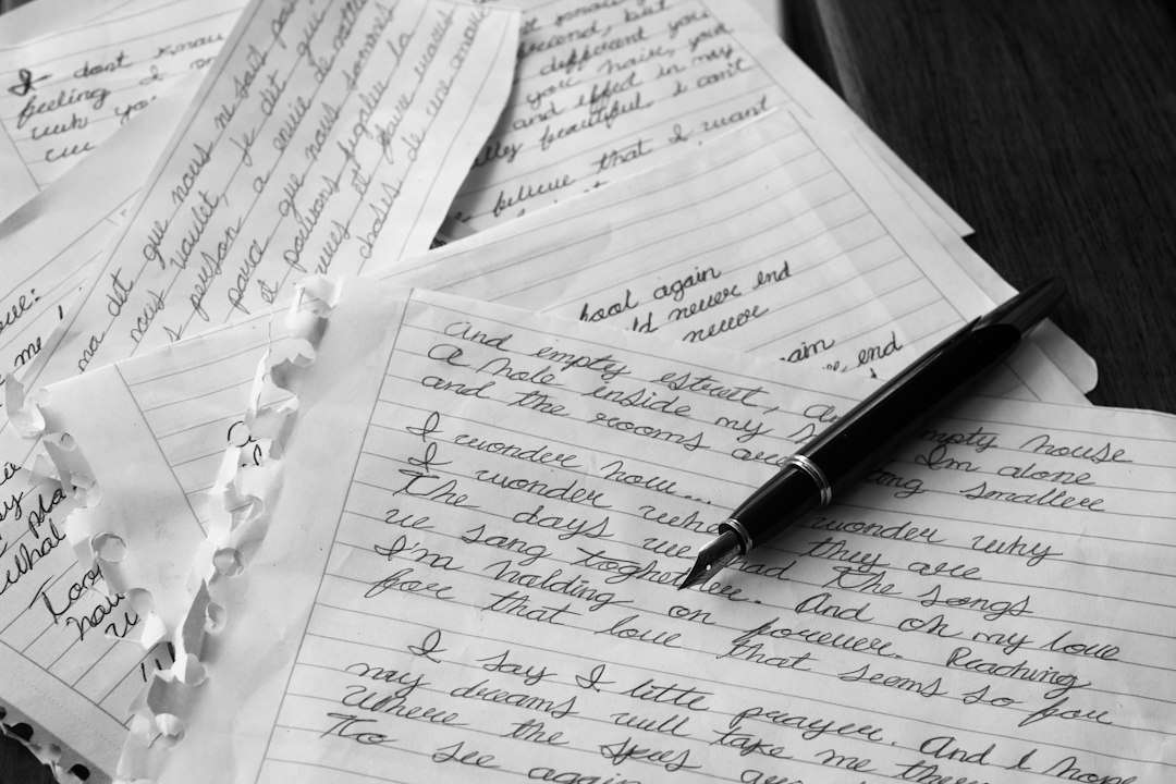 Scattered handwritten notes on a desk, with a pen resting on top of them.