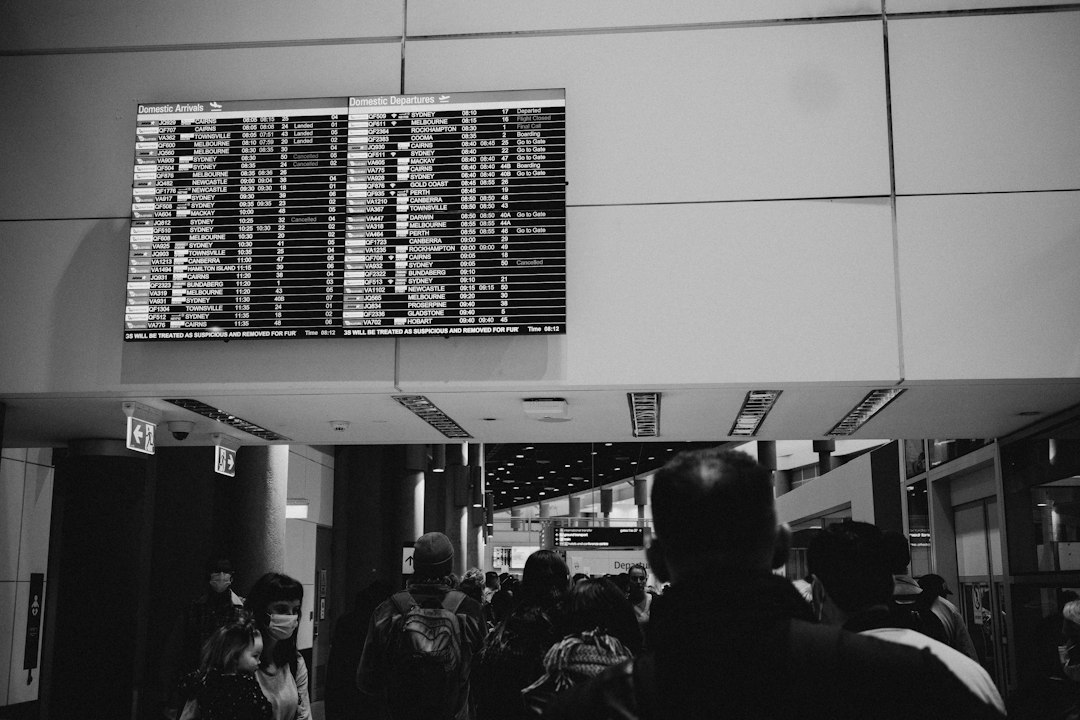 A bustling airport terminal with a large digital flight information screen displaying flight details.