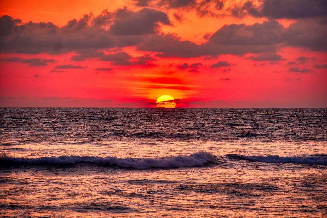 The sun is setting over the ocean, casting a warm glow on the horizon.
