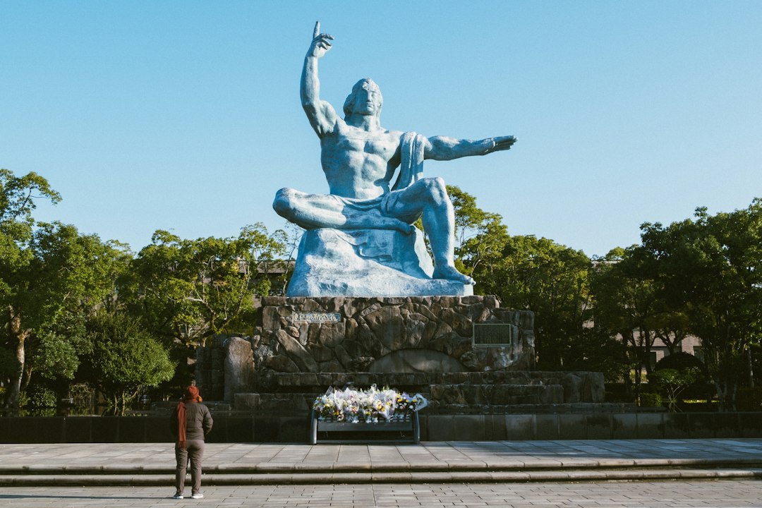 A large bronze statue of a seated human figure, possibly a historical or mythological character, set against a backdrop