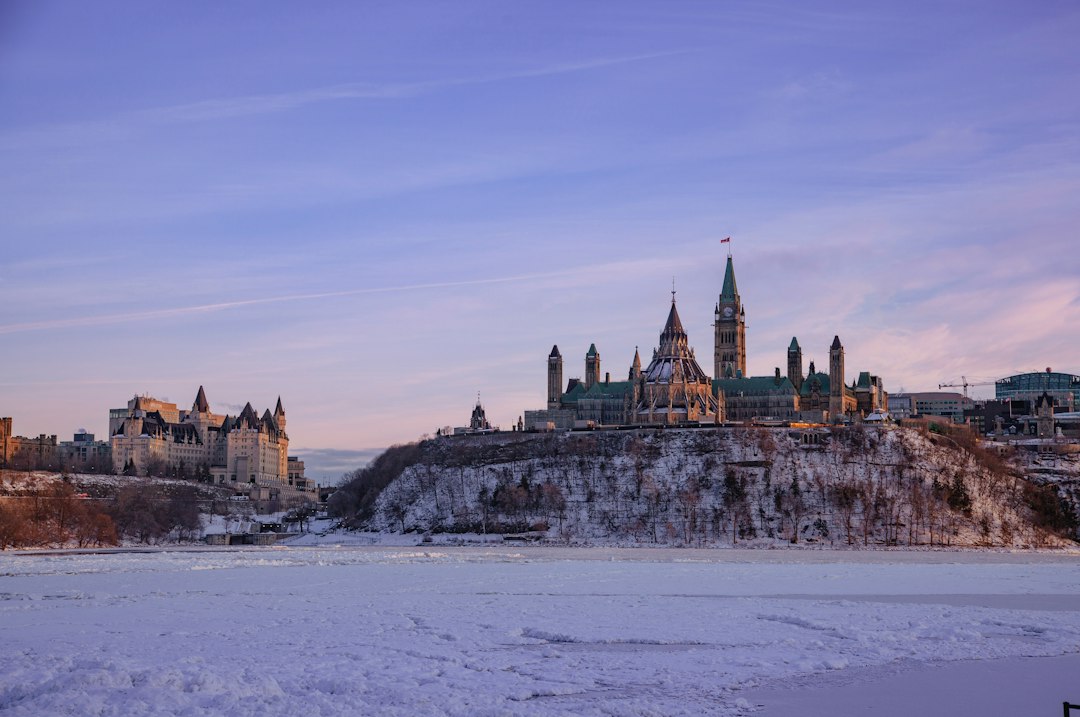Parliament Hill above the frozen Ottawa River at dusk in winter.